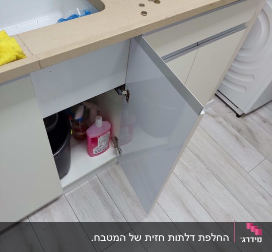 דלת ארון מטבח פתוחה עם ידית אינטגרלית מאלומיניום וצירים גלויים
